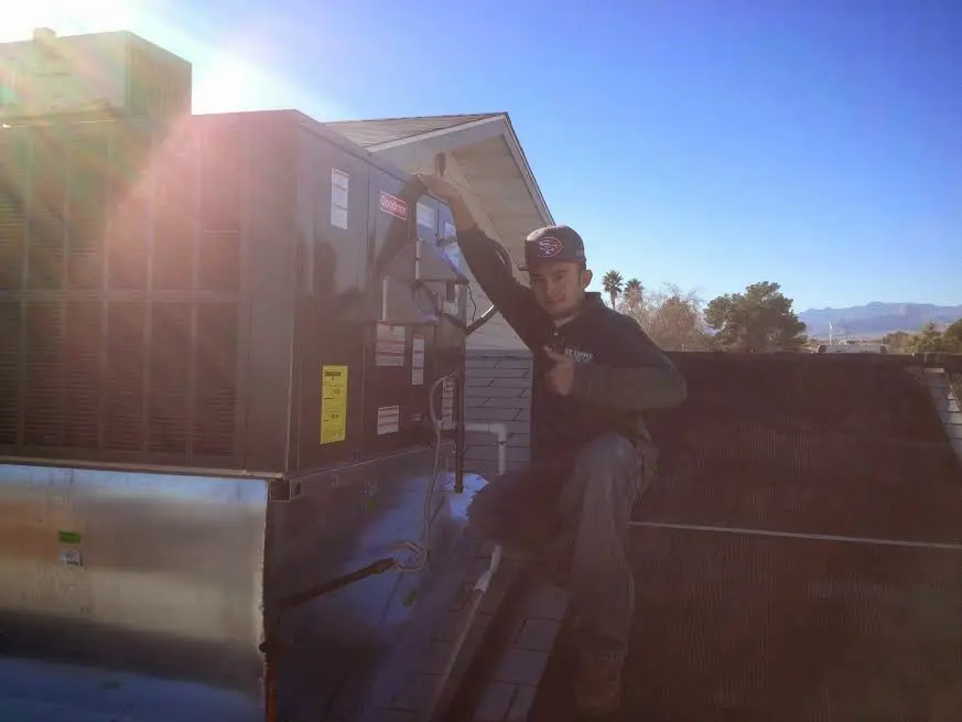 HVAC technician performing Air Duct Repair on a rooftop unit in Morehead City